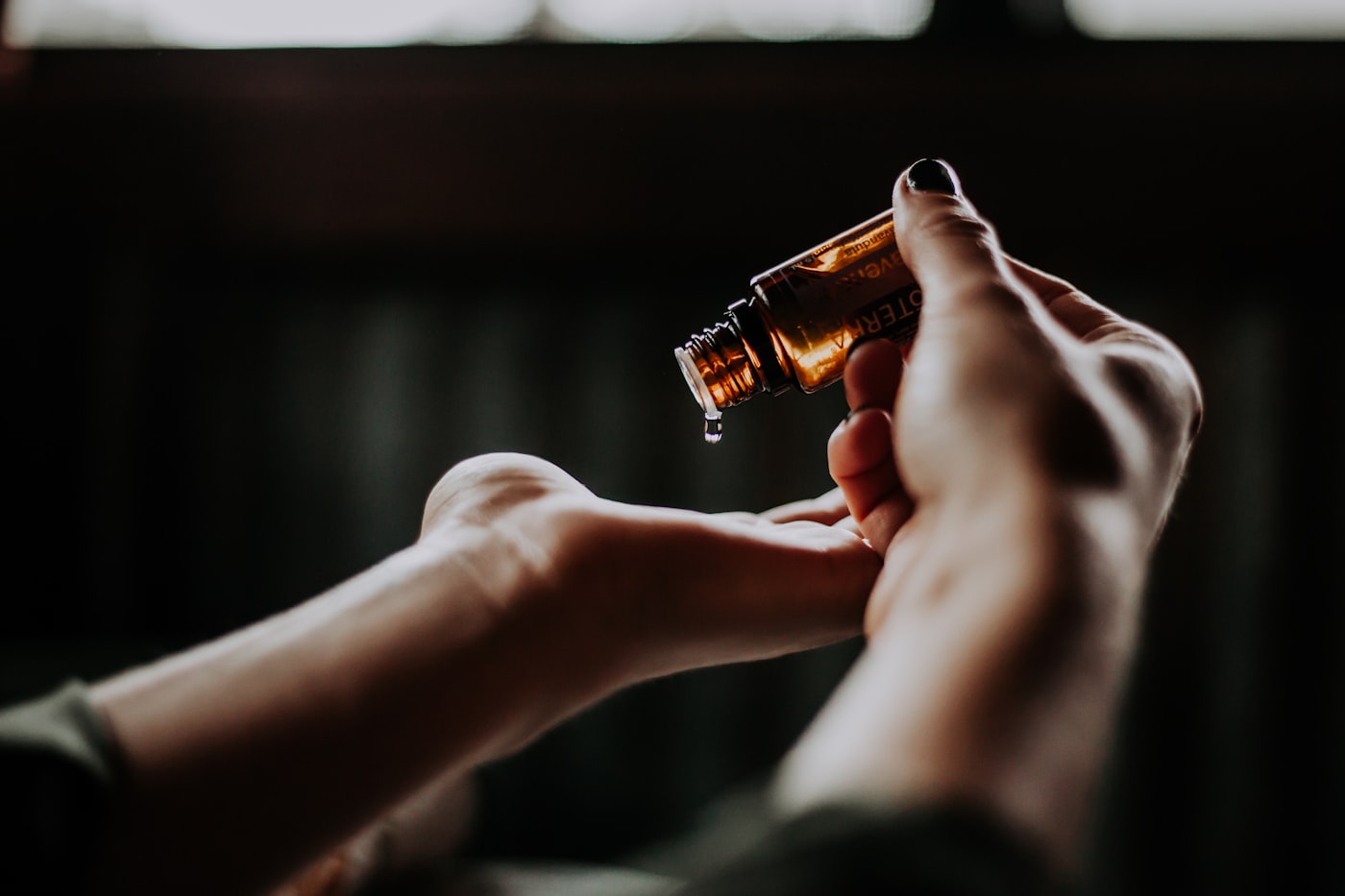 Hands holding a dropper of warm cuticle oil